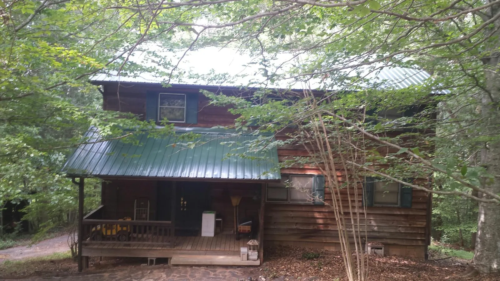 Green metal roof and covered porch on a log cabin in Archbold