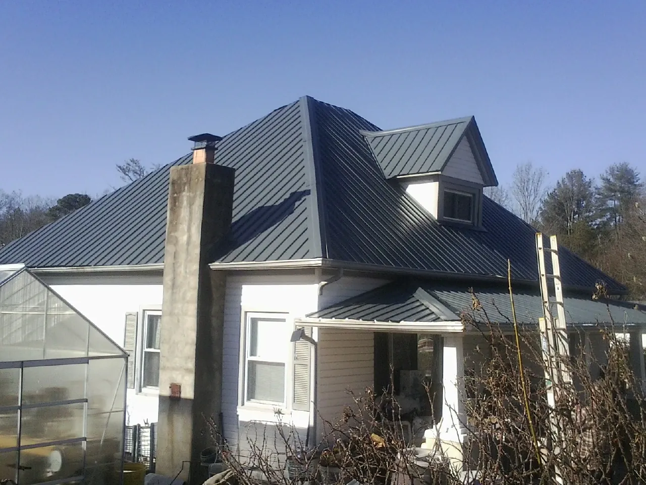 Dark blue standing seam metal roof on a white farmhouse with dormer — Slate & Tile Roof Repair by Roofing Brothers in Archbold