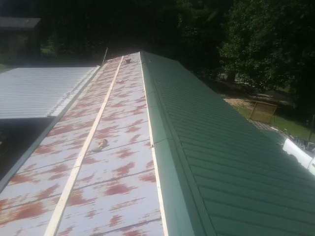 Old rusted panels beside newly installed green metal roofing — Wind Damage Roof Repair by Roofing Brothers in Archbold