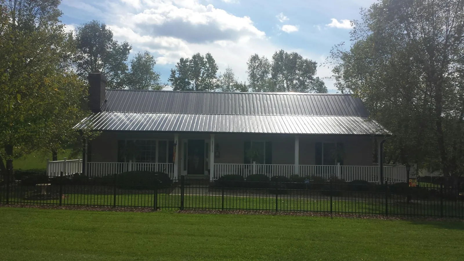 Gray metal roof on a brick ranch with a full width front porch — Gutter Guard Installation work by our crew in Archbold