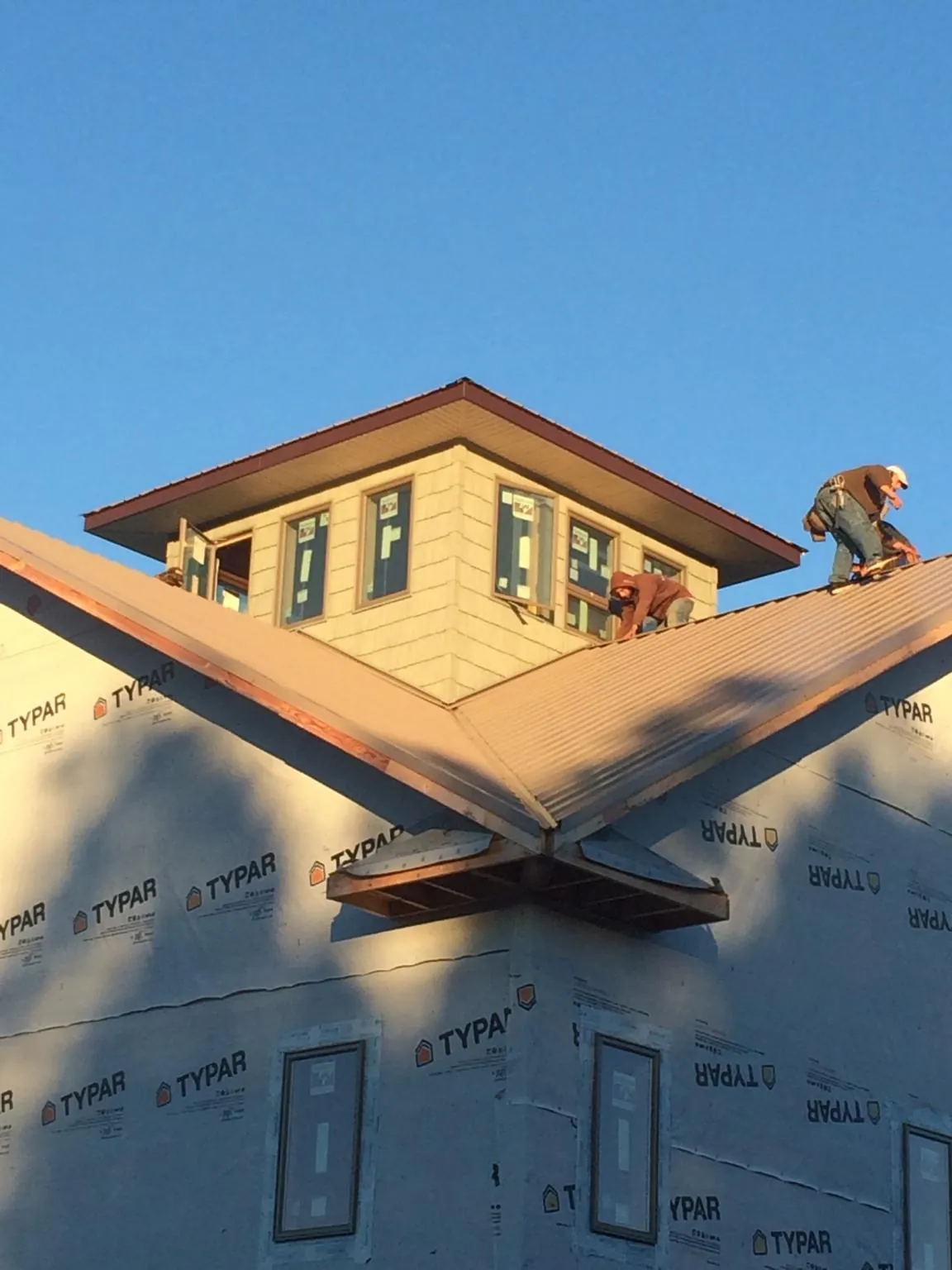 Roofers working around a rooftop cupola on a new metal roof at sunset — Roof Waterproofing in Archbold by Roofing Brothers